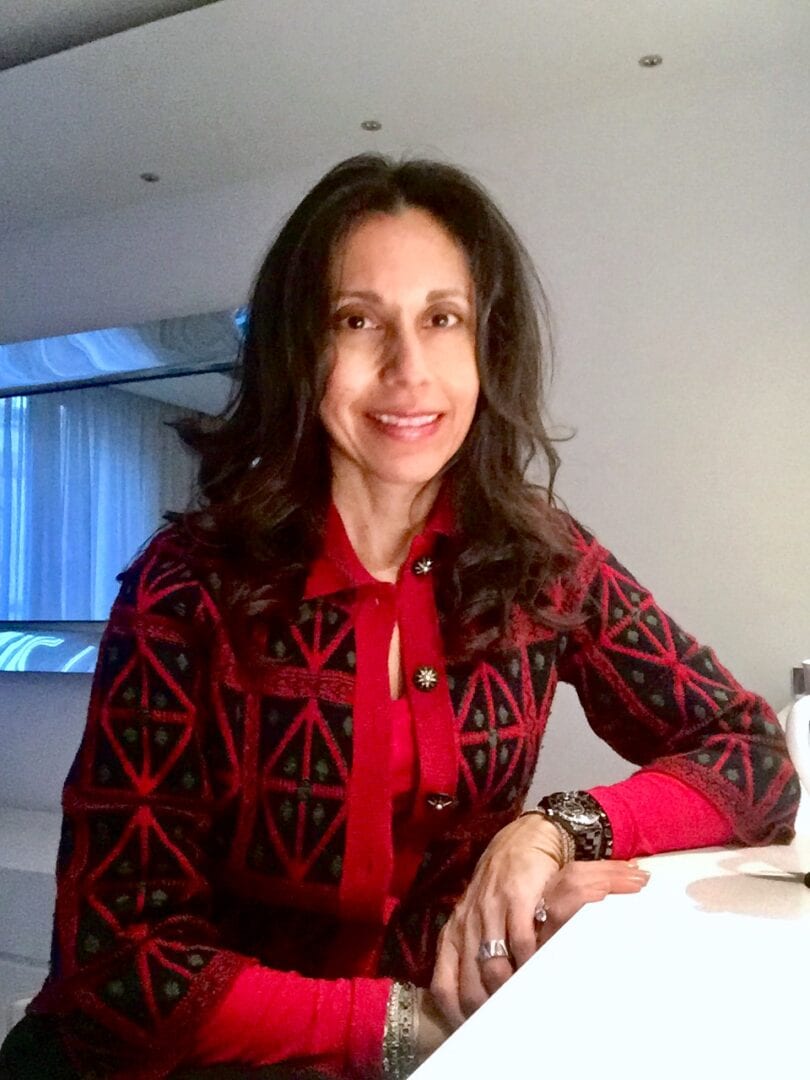 A woman wearing a red and black sweater sitting at a table.