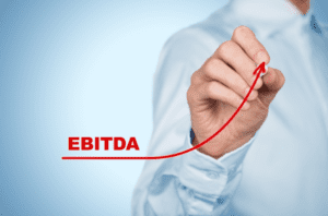 A man is writing the word ebitda on a blue background.
