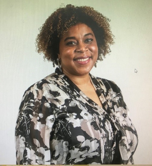 A woman with curly hair is smiling in front of a wall. Beauchamp Consulting offers customized one-on-one consultation based upon individual customer’s specific requirements.