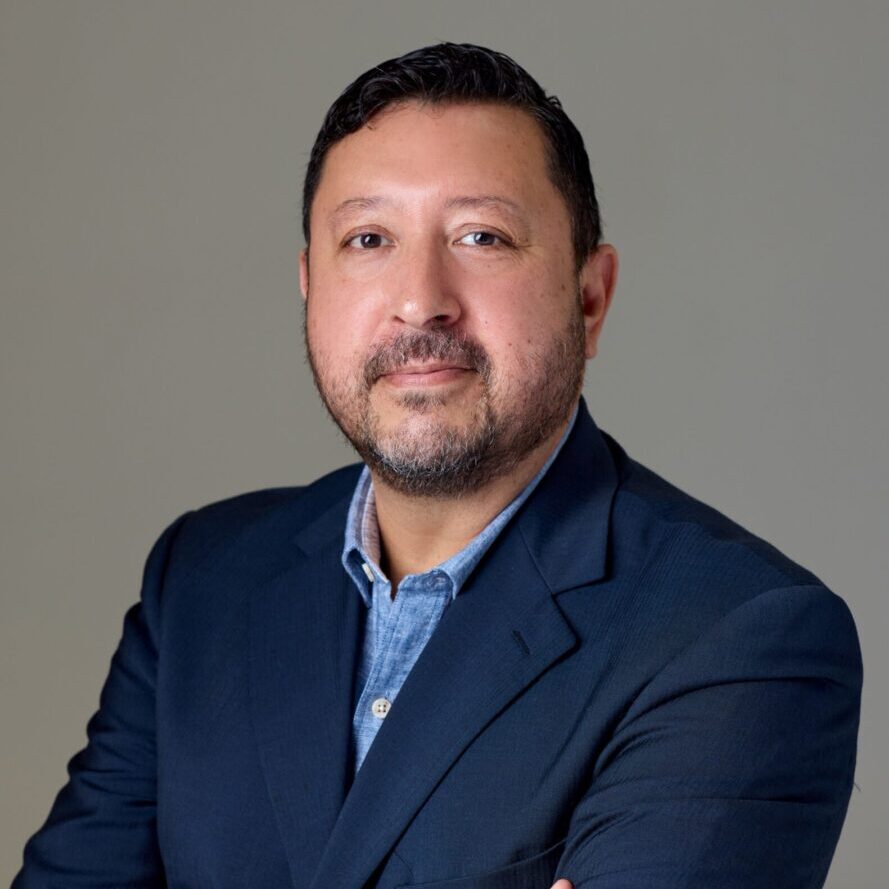 A man in a suit and tie standing with his arms crossed.